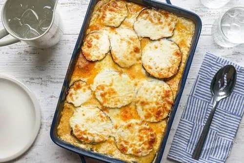 Moussaka grecque gratinée dans un plat, couches d'aubergines et de hachis d'agneau à la tomate nappées de béchamel dorée au four, part découpée.