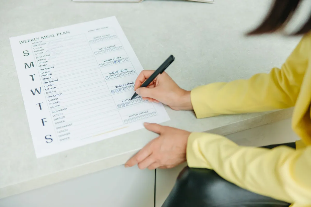 Feuille de planning repas imprimée posée sur un plan de travail, fixée par un aimant