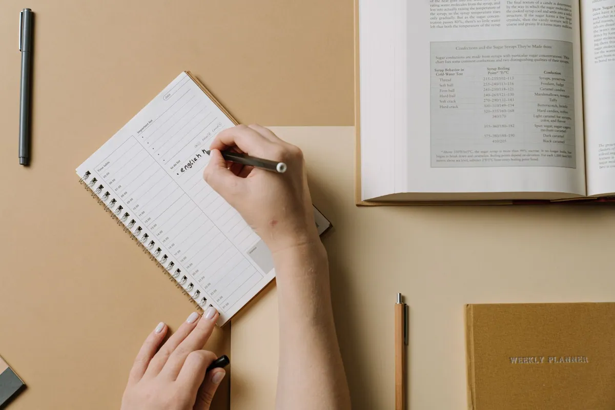 Carnet de planning repas ouvert sur une table de cuisine, avec un stylo et une tasse de café
