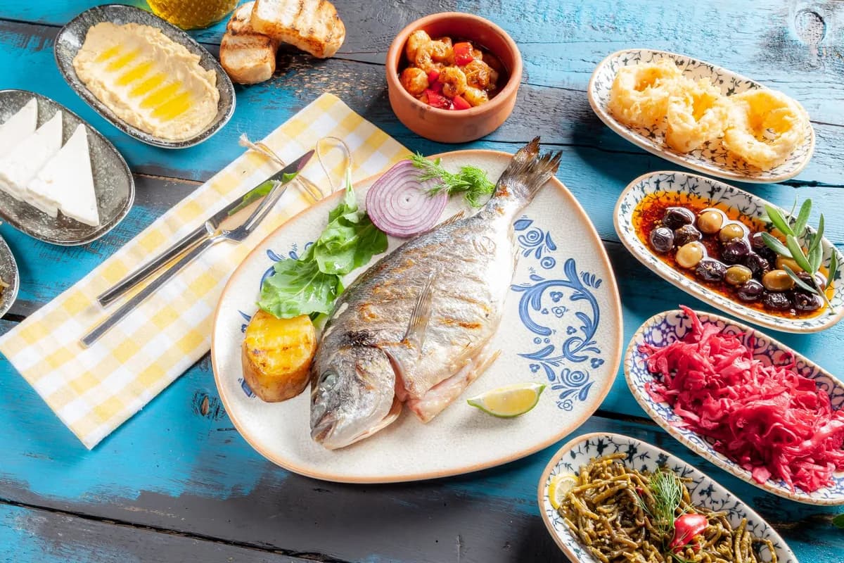 Table méditerranéenne garnie d'huile d'olive, de légumes frais, d'olives, de poisson grillé, de pois chiches et de pain complet