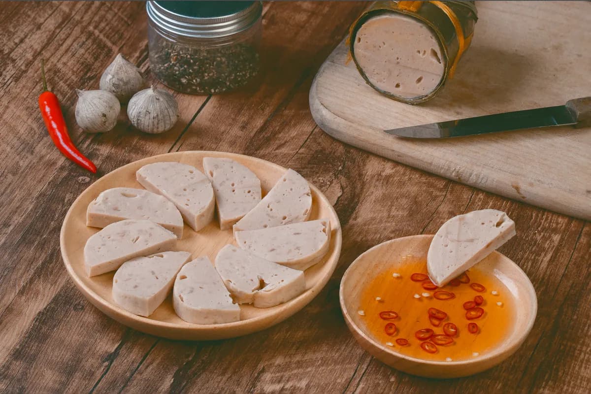 Bún chả hanoïen : galettes et tranches de porc grillées caramélisées trempées dans un bol de nước chấm tiède, servies avec vermicelles de riz et un plateau d'herbes fraîches.