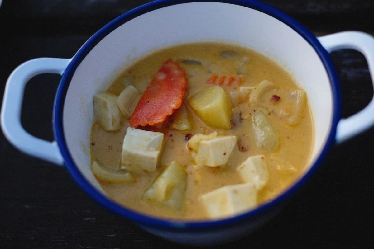 Curry rouge thaïlandais vegan avec tofu doré, poivron, courgette et pois gourmands dans une sauce au lait de coco, servi avec du riz jasmin et du basilic thaï.