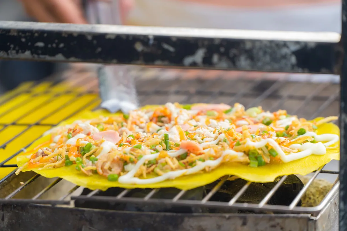 Cuisses de poulet vietnamien grillées et laquées à la citronnelle (gà nướng sả), dorées sur un barbecue, servies avec du riz blanc et des herbes fraîches.