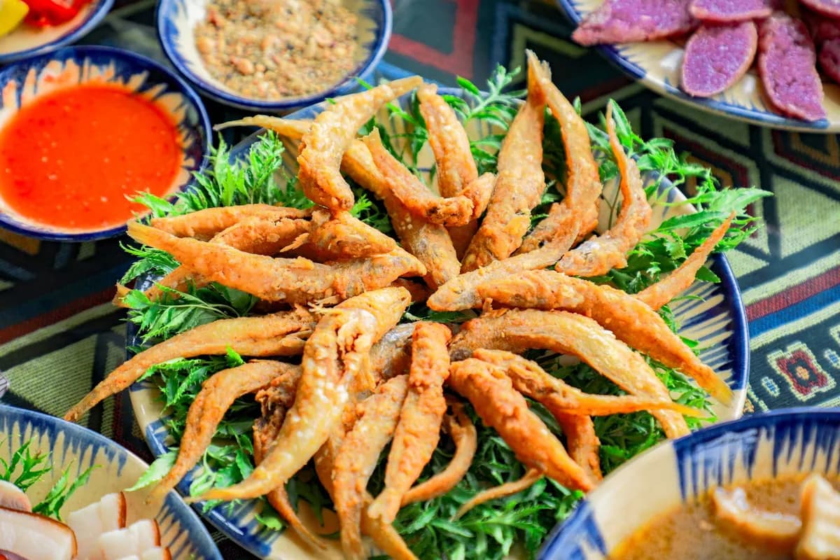 Anchois de la mer Noire (hamsi tava) frits et dorés, disposés en éventail avec quartiers de citron, rondelles d'oignon rouge et roquette.