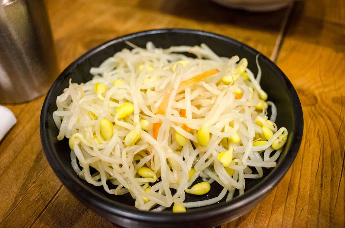 Bol de kongnamul muchim, germes de soja coréens assaisonnés à l'ail, à l'huile de sésame et aux graines de sésame, servi en banchan traditionnel.