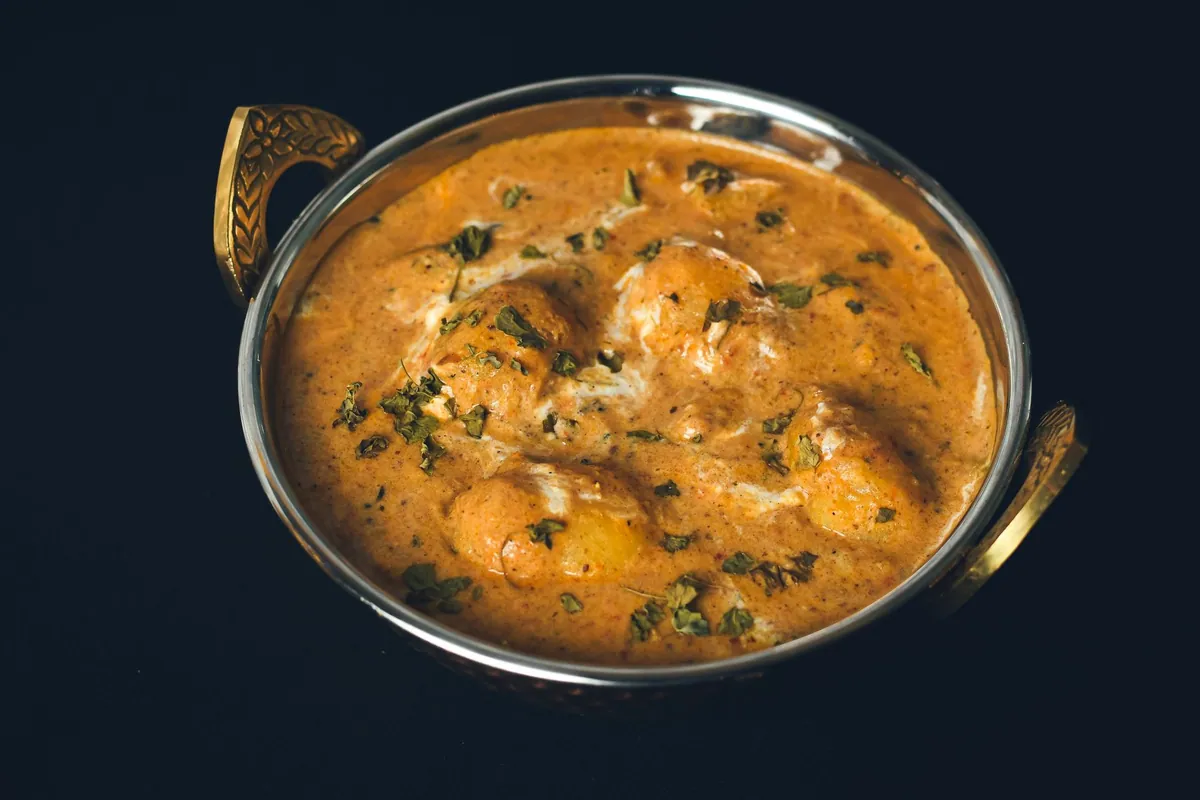 Curry massaman de bœuf thaïlandais dans un bol creux, sauce au lait de coco épaisse, pommes de terre fondantes et cacahuètes concassées, riz jasmin vapeur servi à part.