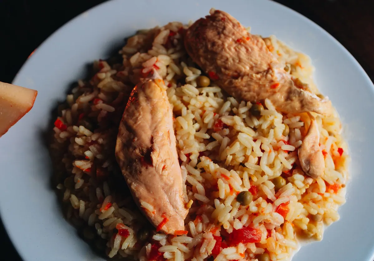 Morceaux de pollo al ajillo dorés avec gousses d'ail en chemise et sauce au vin blanc dans une cocotte, plat espagnol traditionnel parsemé de persil frais.
