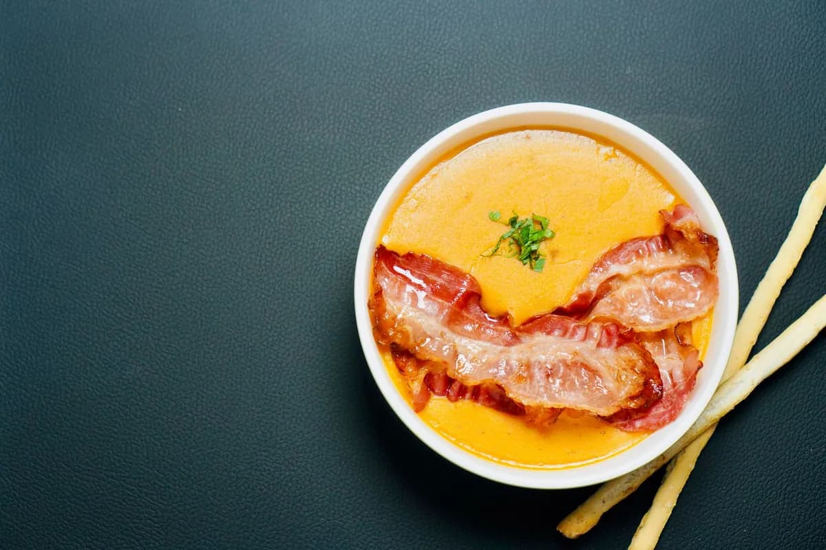 Bol de salmorejo cordobés, crème de tomate épaisse et veloutée couleur brique, garnie d'œuf dur émietté et de fines lamelles de jambon serrano, avec un filet d'huile d'olive.