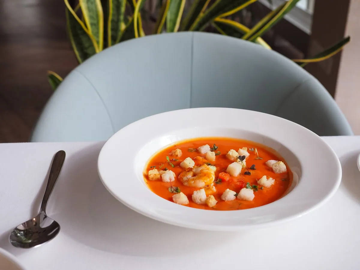 Bol de sopa de tortilla mexicaine : bouillon de tomate garni de lanières de tortillas frites, tranches d'avocat, queso fresco émietté, crème et piment pasilla, parsemé de coriandre fraîche.