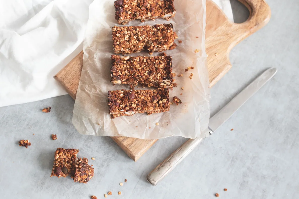 Barres énergétiques aux dattes et amandes empilées sur du papier cuisson