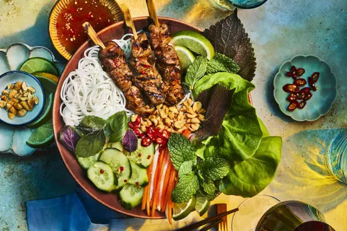Bol de bún thịt nướng avec vermicelles de riz, porc grillé caramélisé, carotte, concombre, herbes fraîches et nước chấm, parsemé de cacahuètes concassées