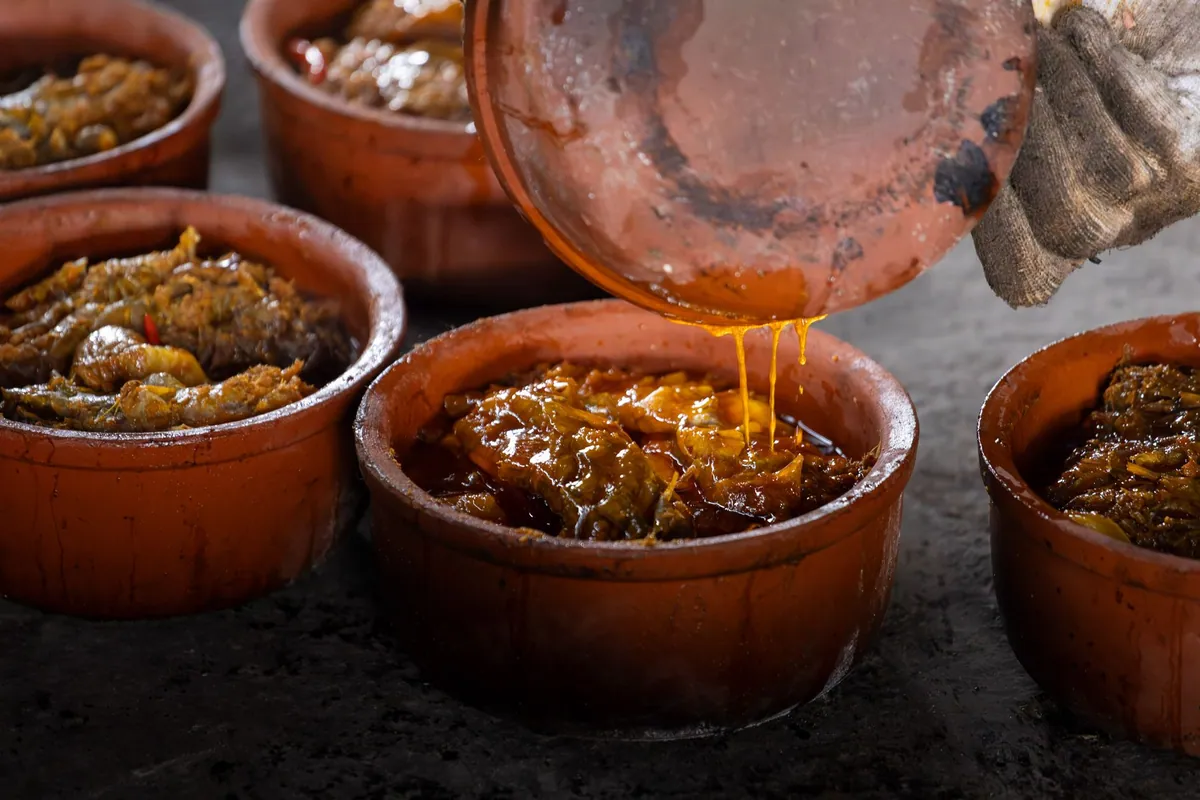 Cá kho tộ, poisson mijoté au caramel dans une cocotte en terre cuite vietnamienne, servi avec du riz blanc et parsemé de cébette.