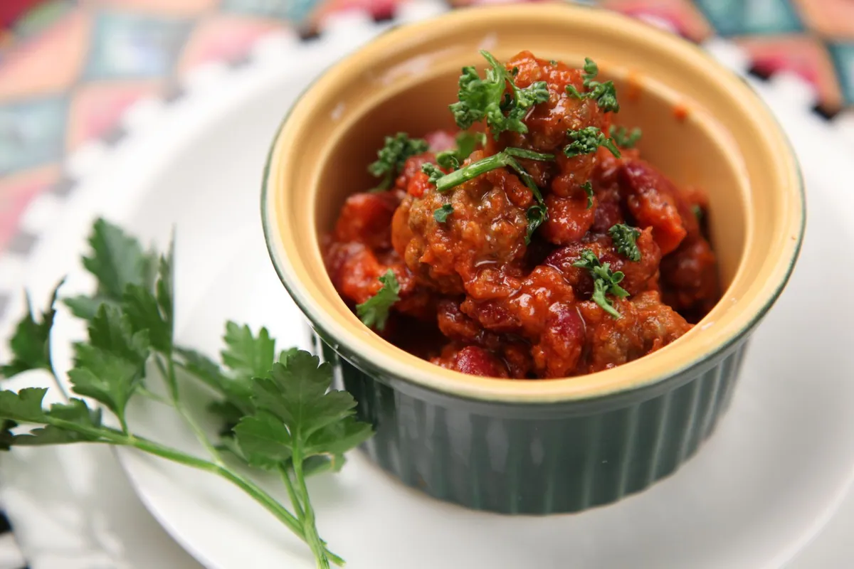Bol de chili con carne fumant garni de cheddar râpé, crème fraîche et coriandre fraîche, servi avec du riz blanc