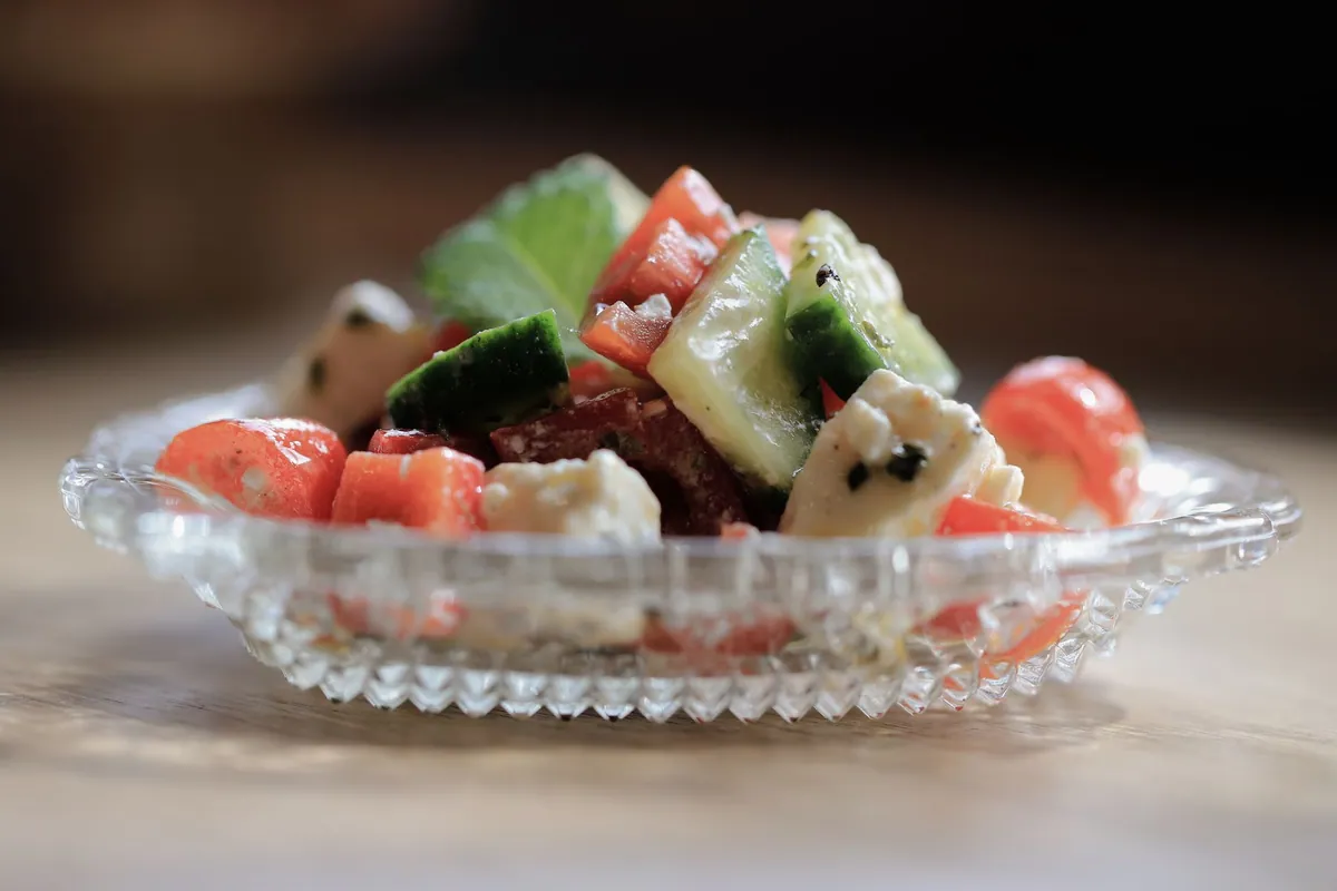 Çoban salatası, salade turque du berger avec tomates, concombre, oignon et poivron en petits dés, persil et huile d'olive, servie dans un bol blanc.