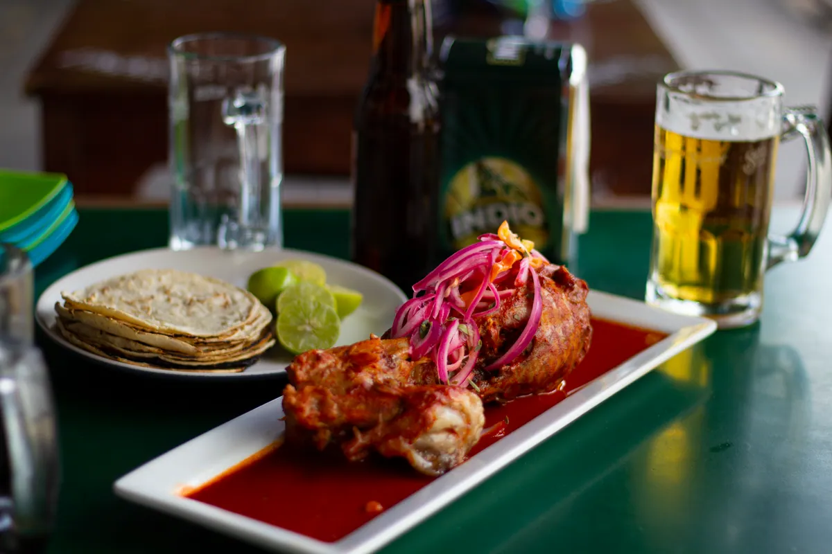 Cochinita pibil effilochée servie sur une feuille de bananier avec oignons rouges marinés au habanero et tortillas de maïs chaudes