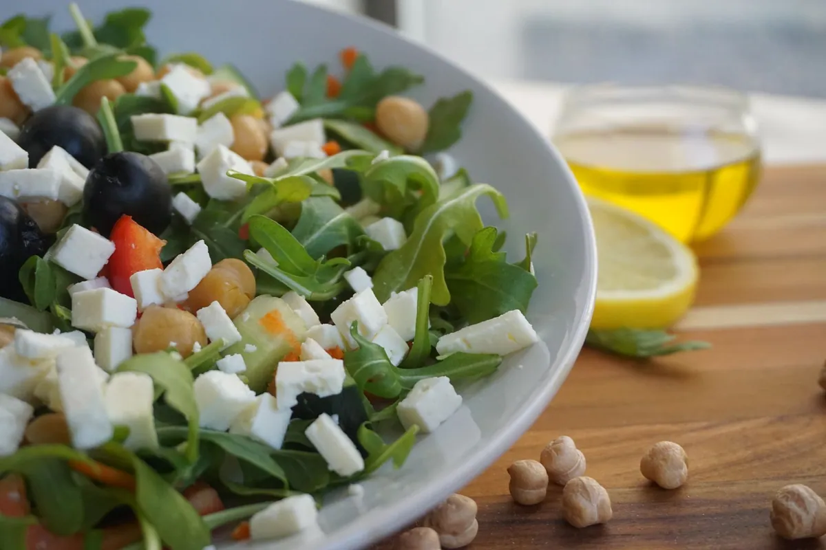 Salade de pois chiches ensalada de garbanzos avec poivron rouge, tomates, concombre et oignon rouge dans un saladier, arrosée d'huile d'olive.