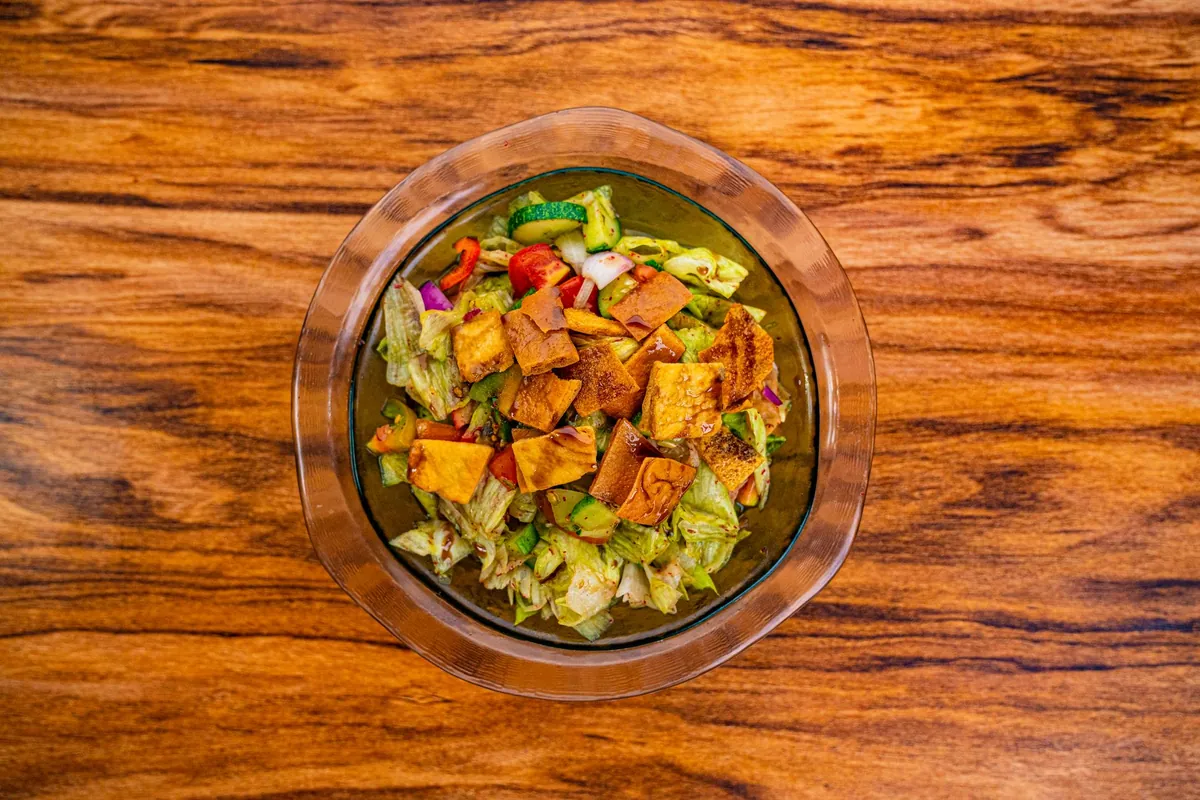 Salade fattouche libanaise avec laitue, tomates, concombre, radis, herbes fraîches et chips de pita croustillantes, nappée d'une vinaigrette au sumac et à la mélasse de grenade.