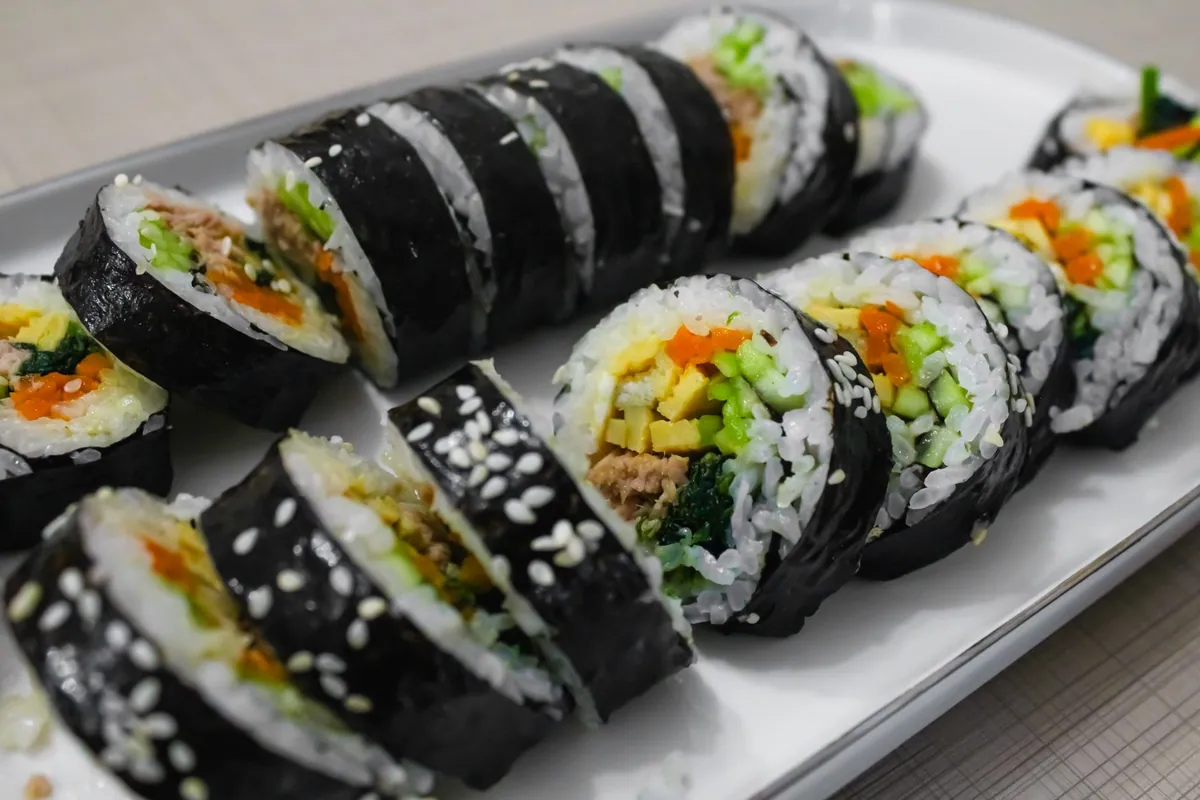 Rondelles de gimbap coréen tranchées, montrant le riz, l'omelette, la carotte, les épinards et le bœuf enroulés dans une feuille de nori.