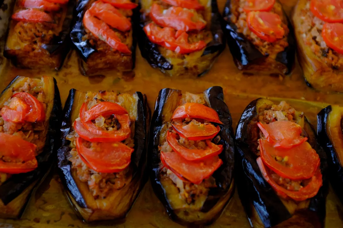 Aubergines imam bayıldı farcies d'oignons et de tomates, confites dans l'huile d'olive, servies froides sur un plat garni de persil et de citron