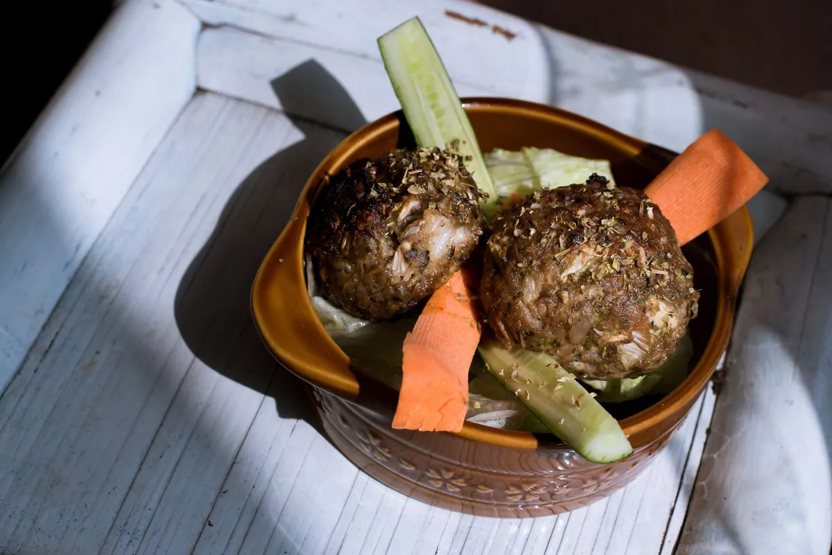Boulettes de viande grecques keftedes dorées à la poêle, servies avec tzatziki, quartiers de citron et menthe fraîche sur un plateau de meze.