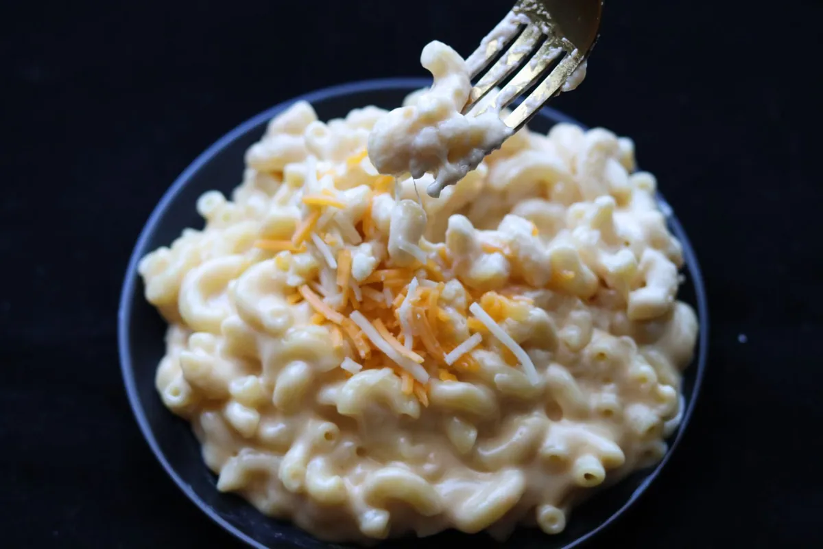 Plat de mac and cheese gratiné au four, macaronis nappés de sauce au cheddar recouverts d'une chapelure dorée et croustillante, servi dans un plat en céramique.