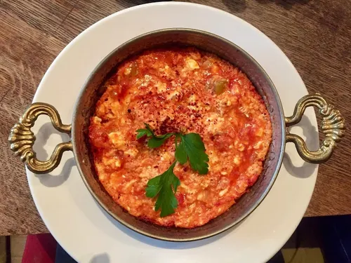 Poêle de menemen turc, œufs brouillés crémeux aux tomates et poivrons verts saupoudrés de pul biber, servi avec du pain frais