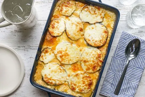 Moussaka grecque gratinée dans un plat, couches d'aubergines et de hachis d'agneau à la tomate nappées de béchamel dorée au four, part découpée.