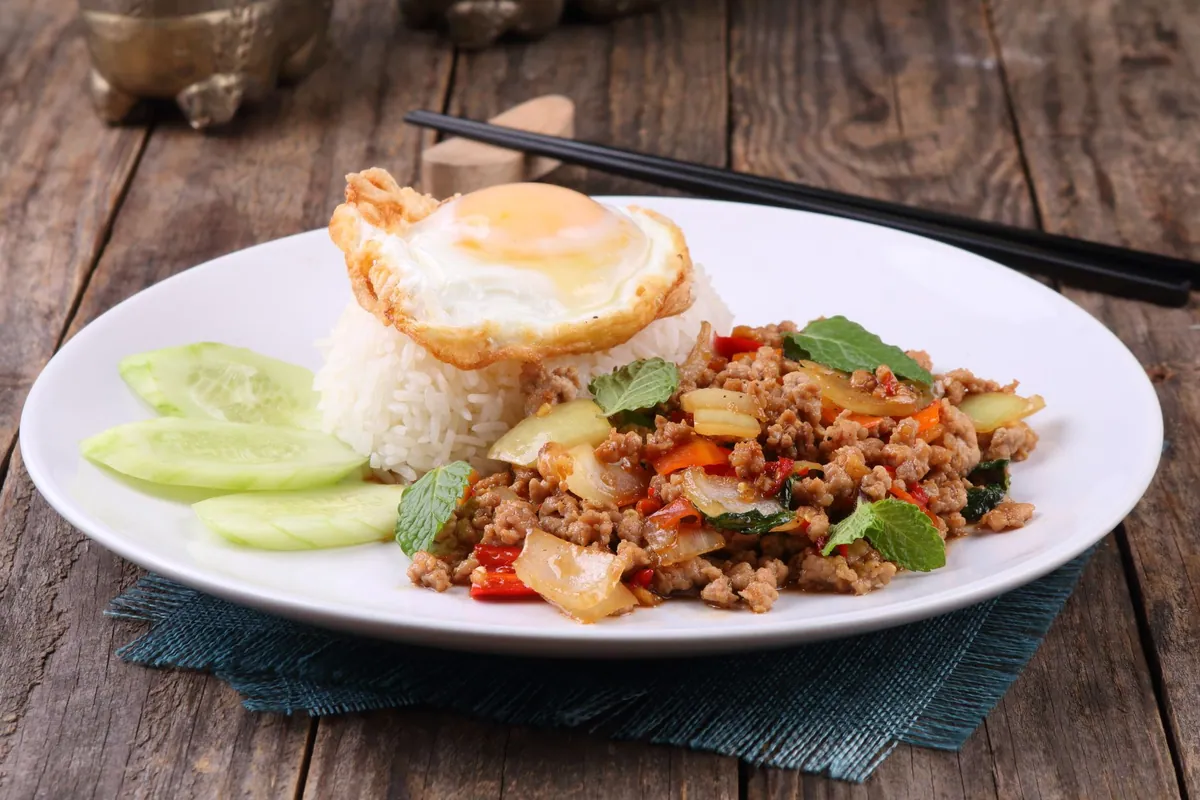 Pad kra pao thaïlandais : bœuf haché sauté au basilic sacré, ail et piment, servi sur riz jasmin et surmonté d'un œuf au plat aux bords croustillants.