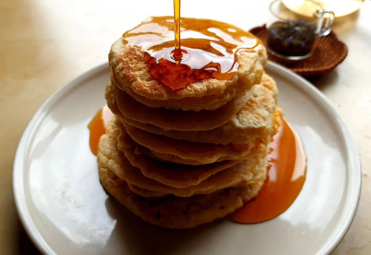 Pile de pancakes moelleux nappés de sirop d'érable avec une noisette de beurre