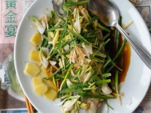 Filet de poisson cuit à la vapeur cantonaise, nappé de sauce soja, gingembre et oignons nouveaux, arrosé d'huile fumante et parsemé de coriandre fraîche