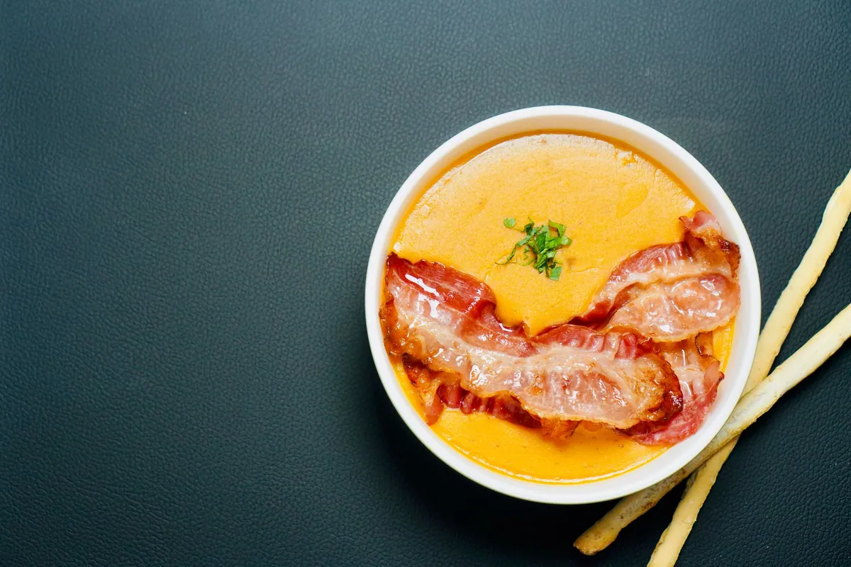 Bol de salmorejo cordobés, crème de tomate épaisse et veloutée couleur brique, garnie d'œuf dur émietté et de fines lamelles de jambon serrano, avec un filet d'huile d'olive.