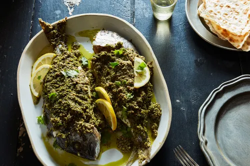 Filets de poisson samké harra nappés de sauce tahini à l'ail et au citron, parsemés de noix et pignons de pin torréfiés et de coriandre fraîche.