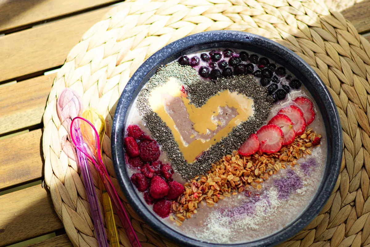 Smoothie bowl violet garni de fruits rouges frais, granola et graines de chia