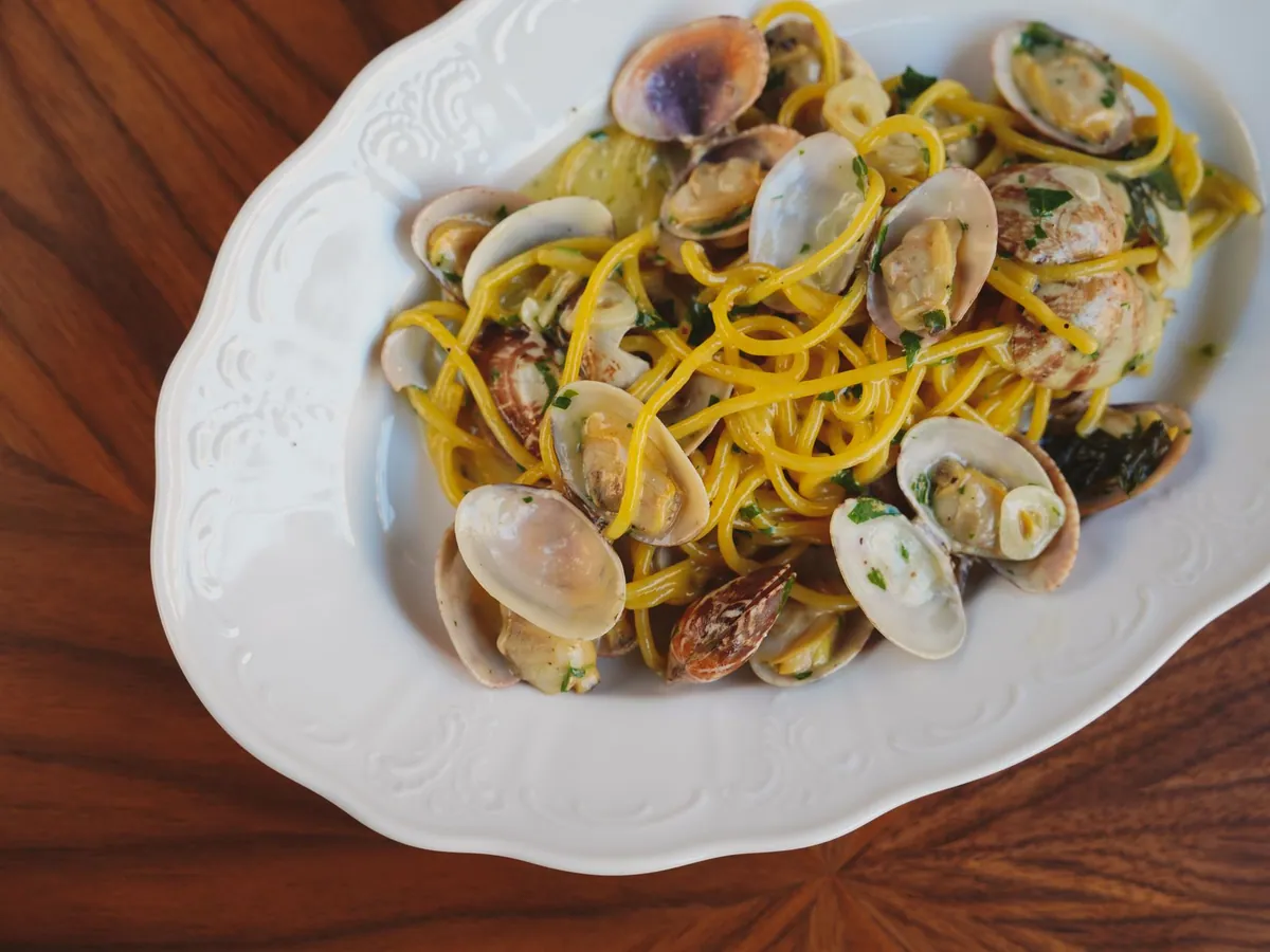 Assiette de spaghetti alle vongole napolitains, palourdes ouvertes dans une sauce à l'huile d'olive, à l'ail et au persil, servis dans une assiette creuse.
