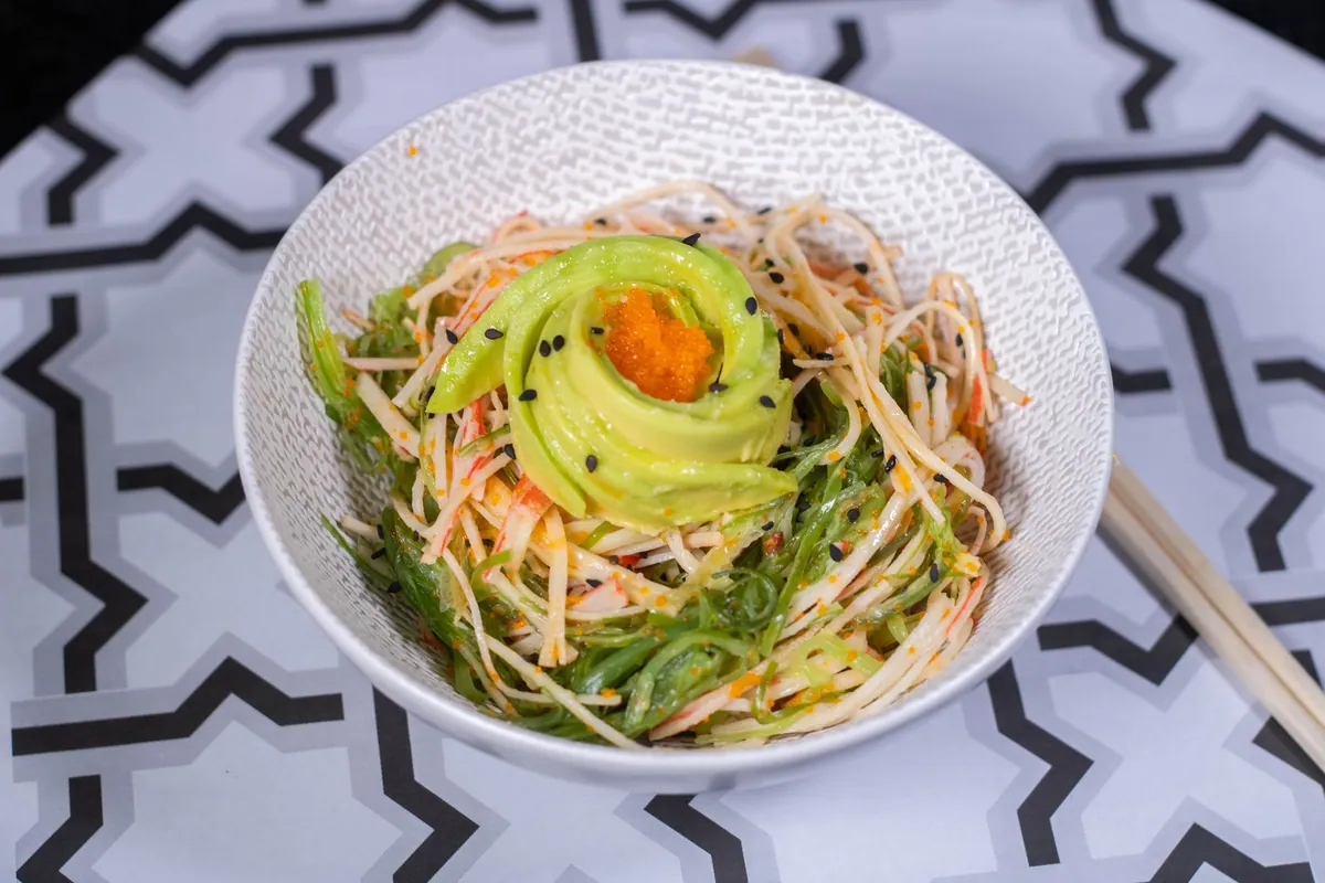 Sunomono au concombre et wakame dans un petit bol japonais, tranches de concombre translucides et algues marinées parsemées de sésame grillé.