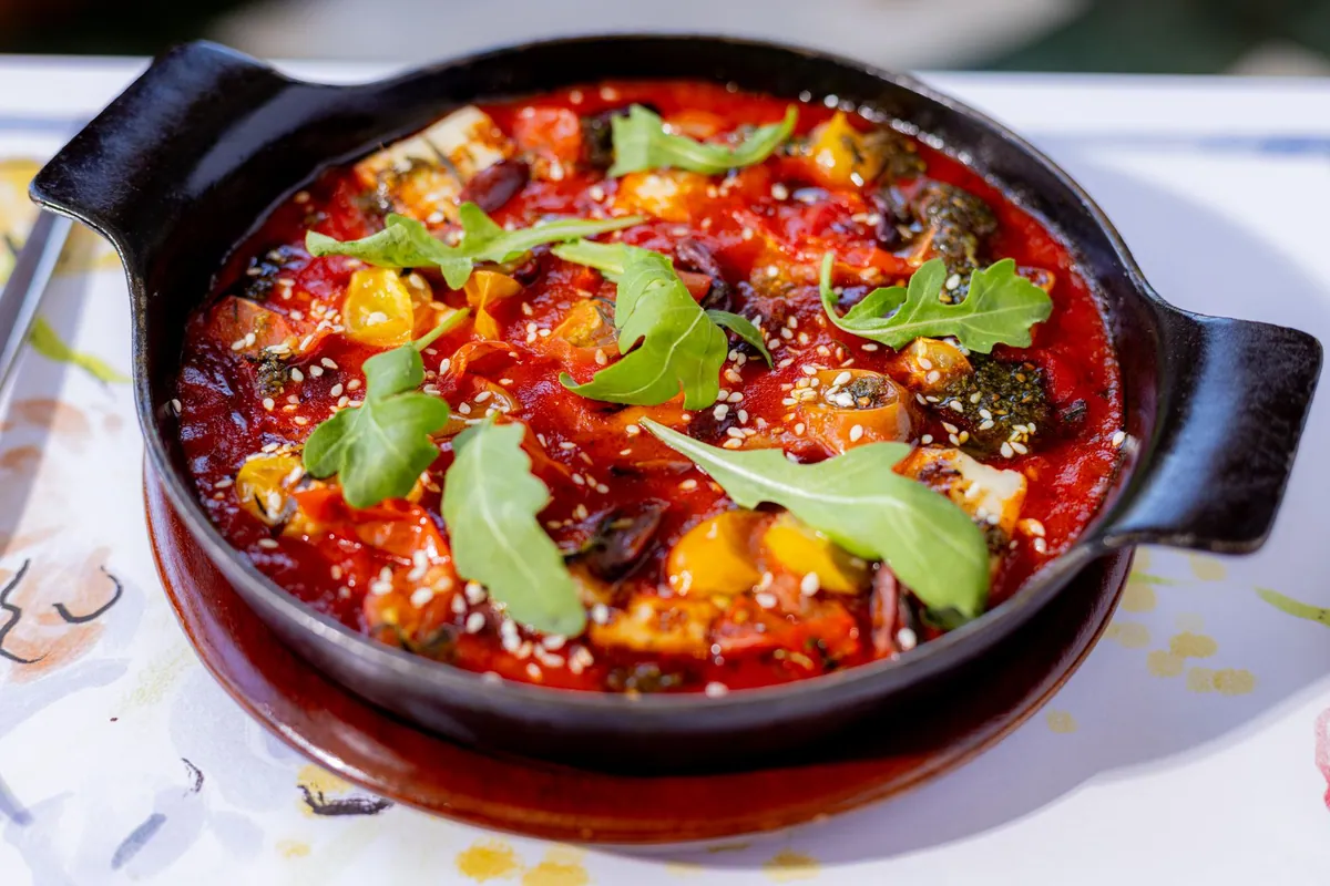 Bol de taktouka marocaine, compotée de poivrons grillés et de tomates parsemée de coriandre et de persil frais, arrosée d'un filet d'huile d'olive.