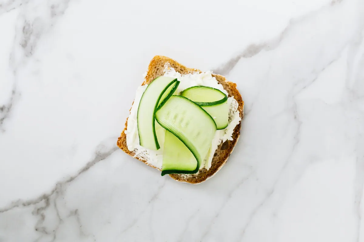 Tartine de pain de campagne garnie de fromage frais, rondelles de concombre et menthe fraîche